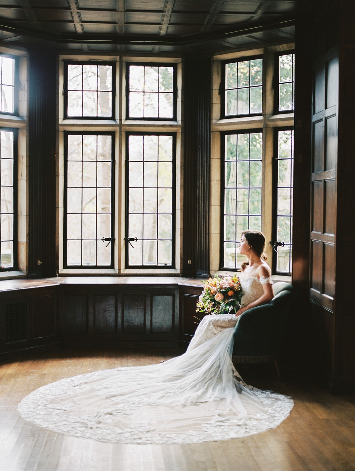Bride in elegant lace wedding gown near bay window