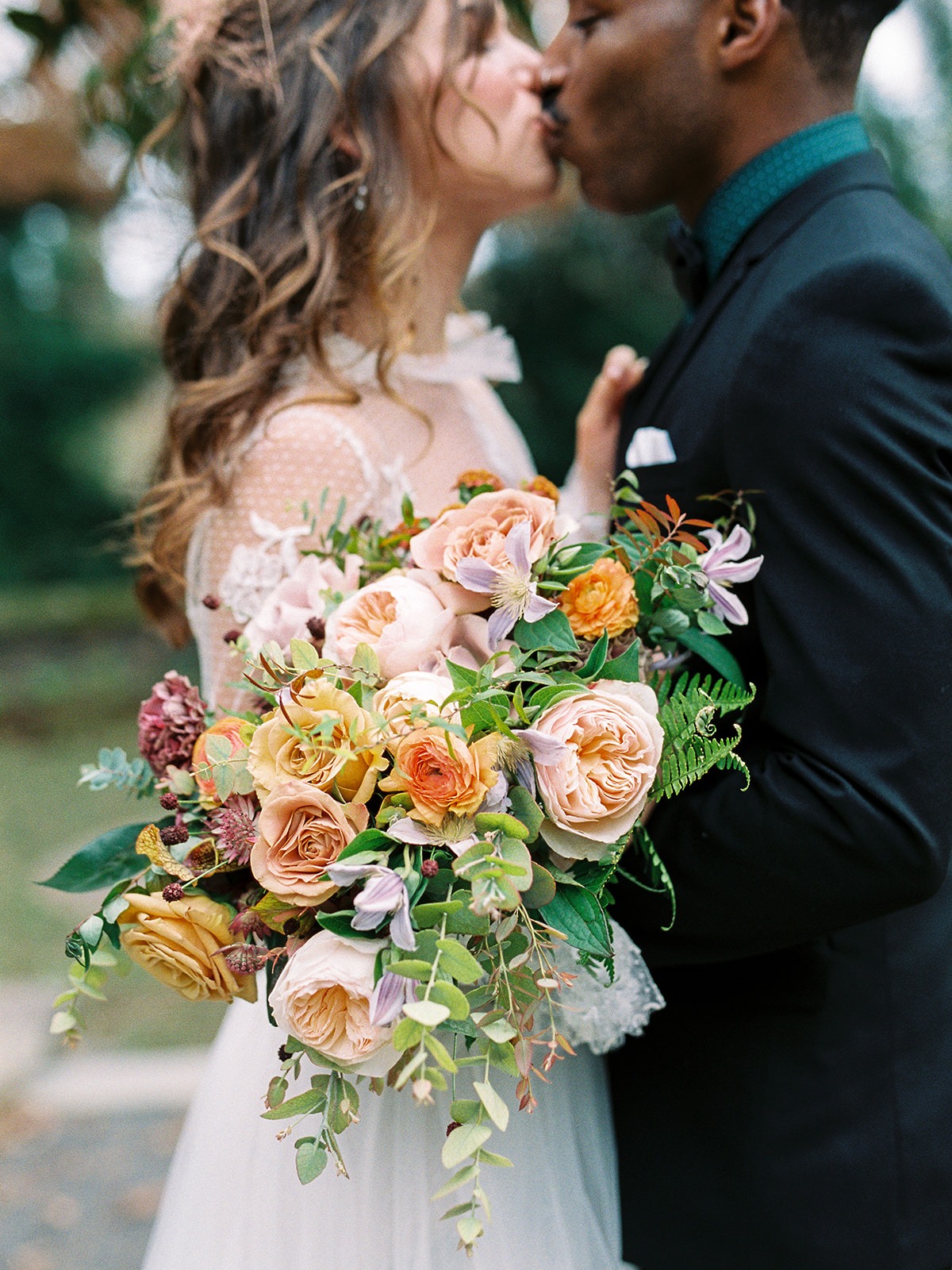 Elegant couple kissing with a beautiful floral bouquet on their wedding day