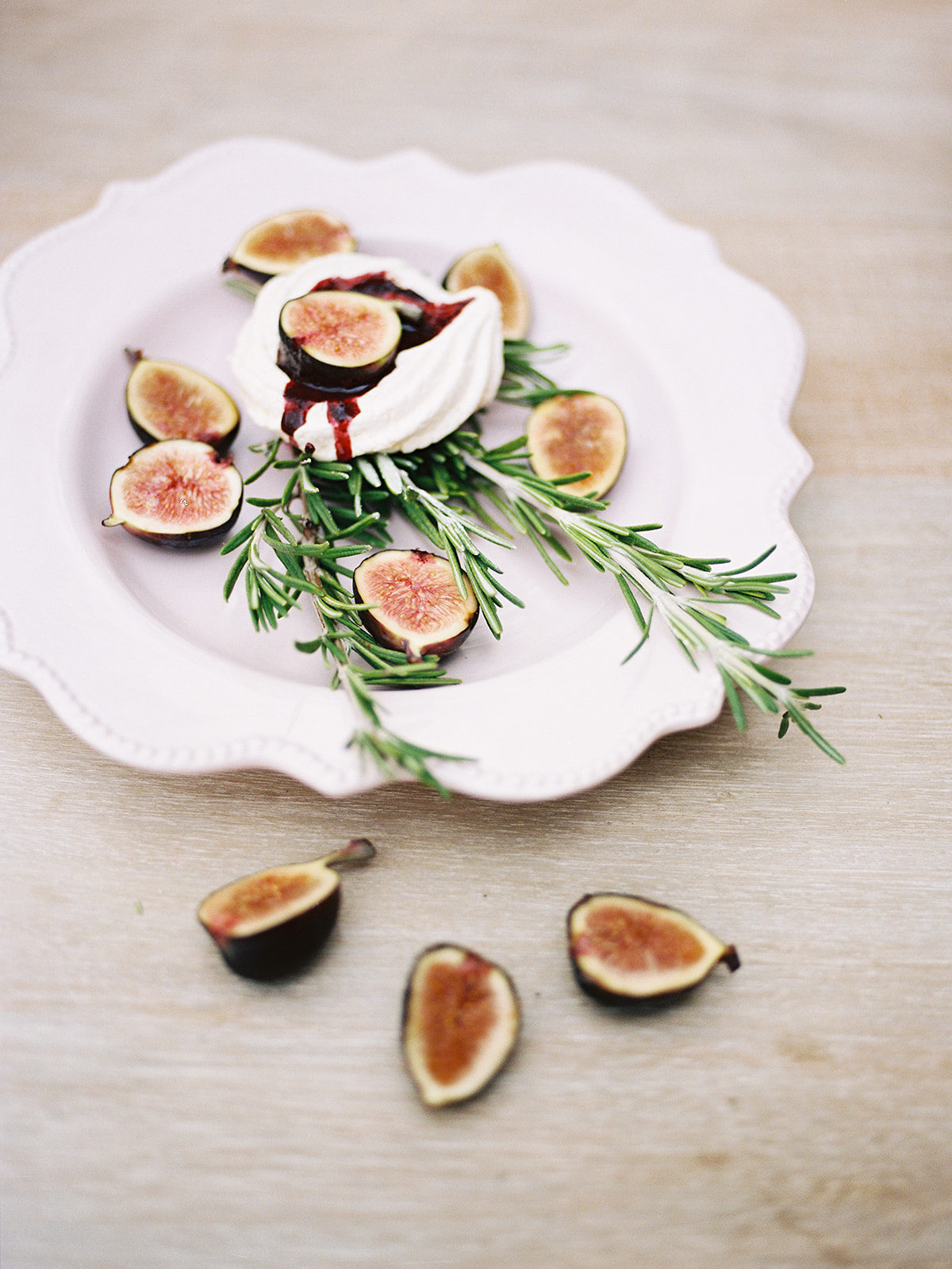 Fresh figs with creamy topping and rosemary on a white plate