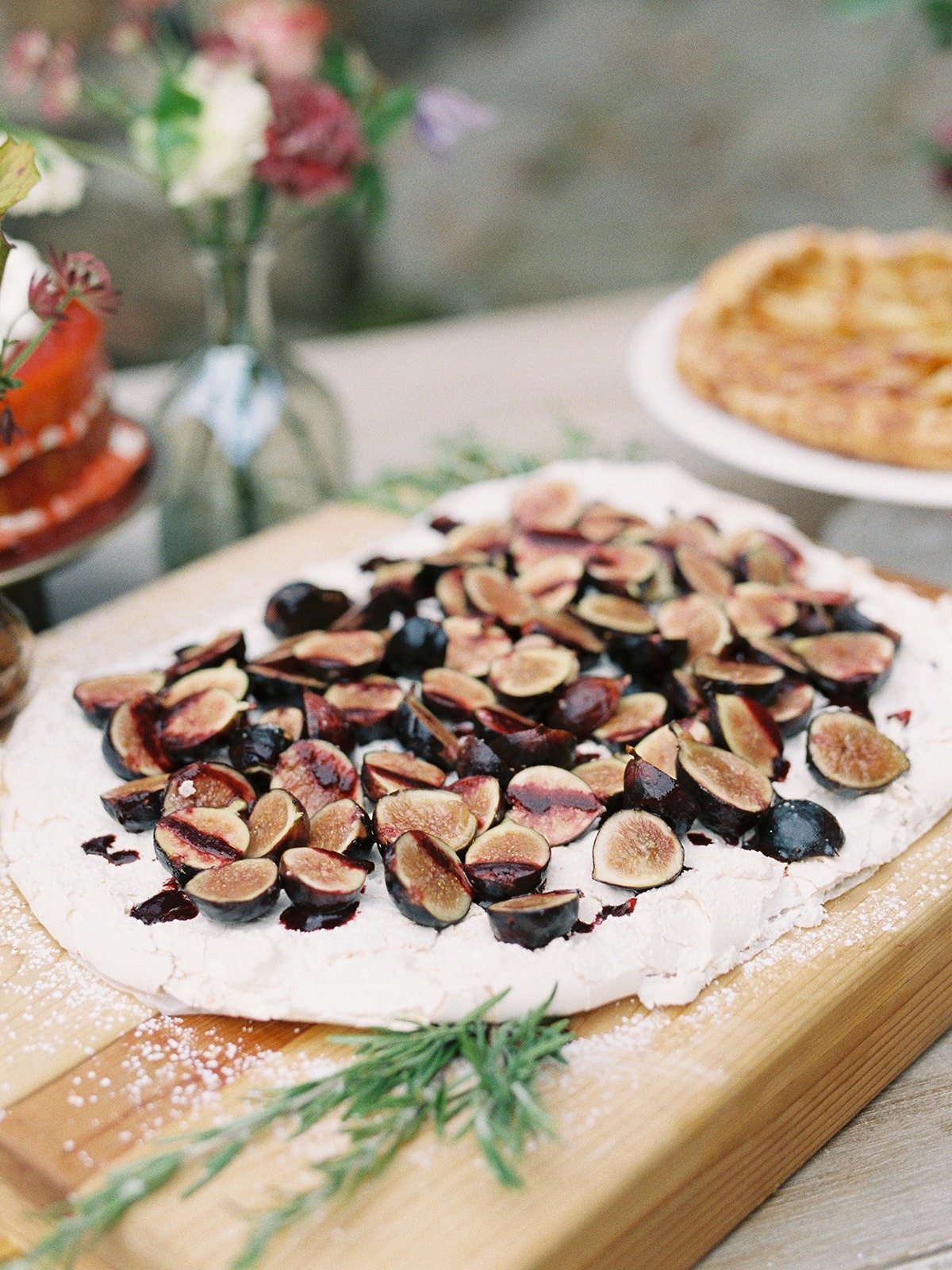 Fig tart with rosemary on a wooden board with flowers and pie