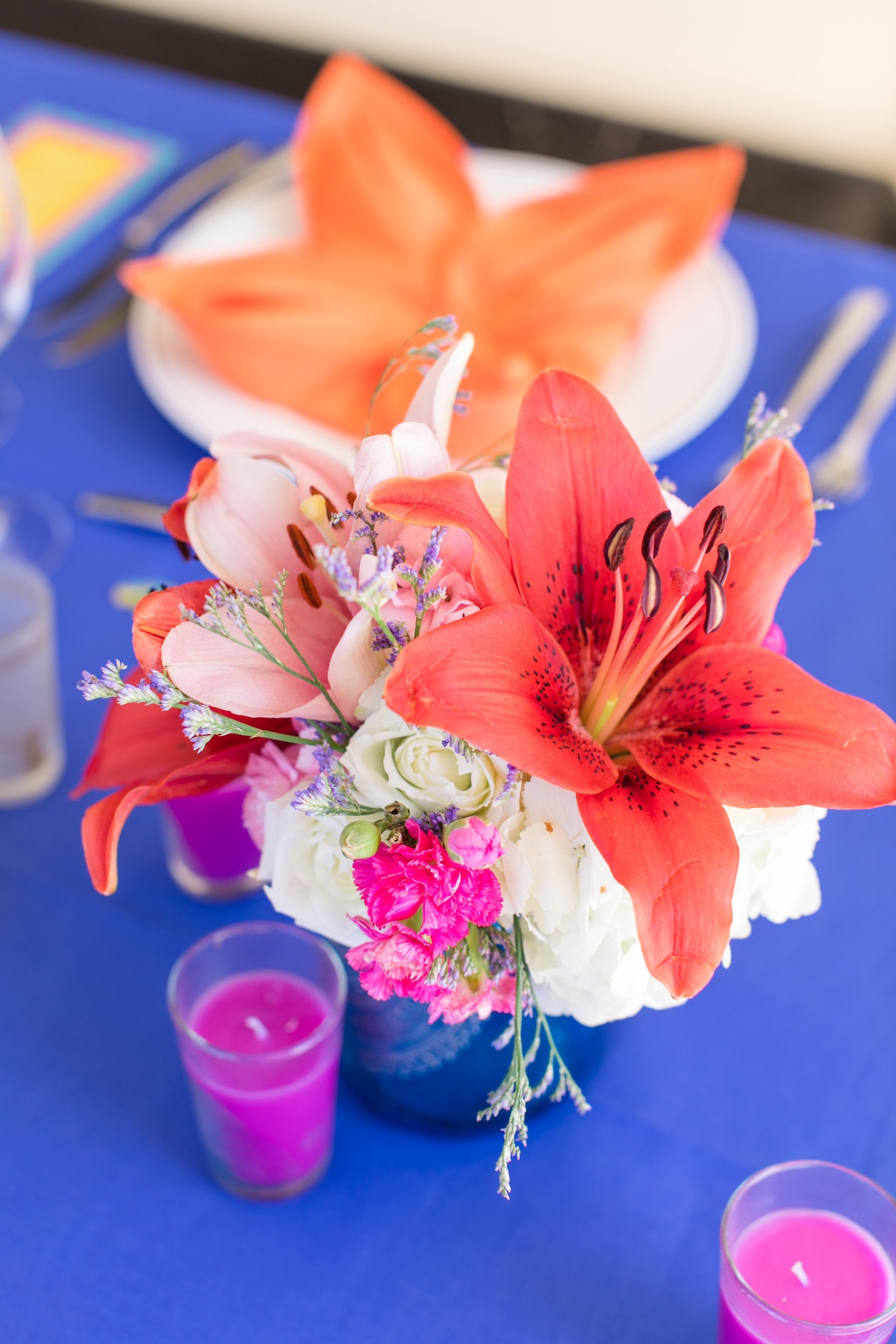 Bright table setting with lily centerpiece and orange napkin