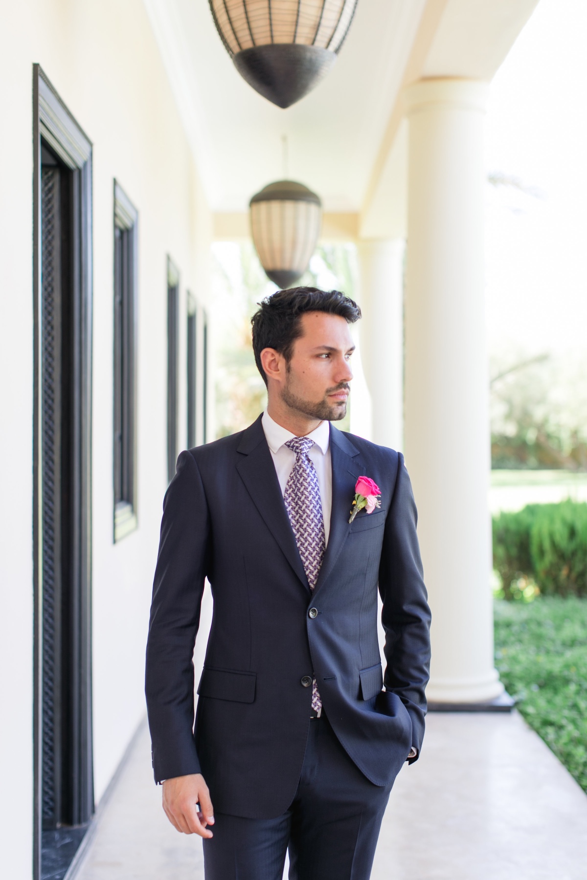 Groom in navy suit, patterned tie, and boutonniere