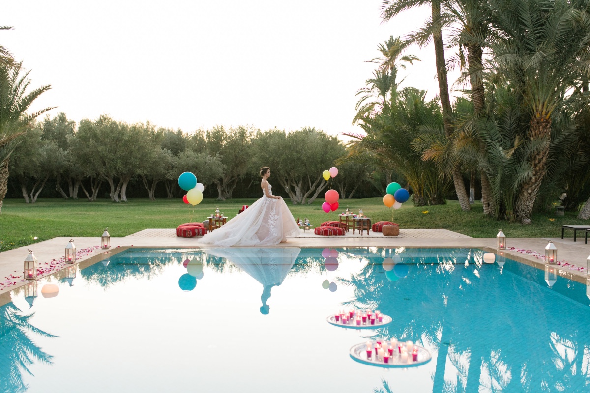 Bride standing by a pool in a tropical wedding scene