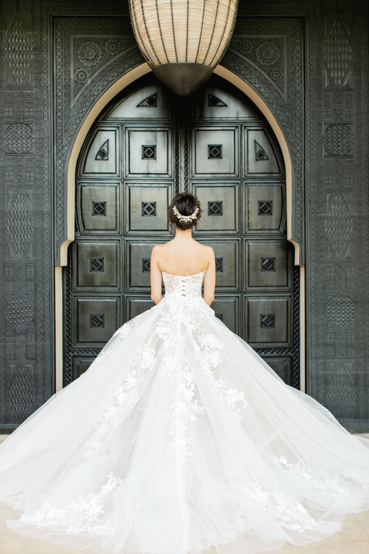 Bride in white gown stands before ornate Moroccan doorway