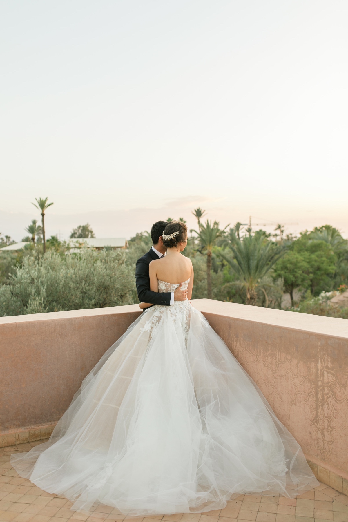 Elegant bride and groom embrace overlooking a lush landscape