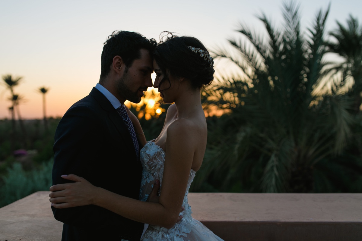 Romantic wedding couple embraces during a beautiful sunset, palms in the background