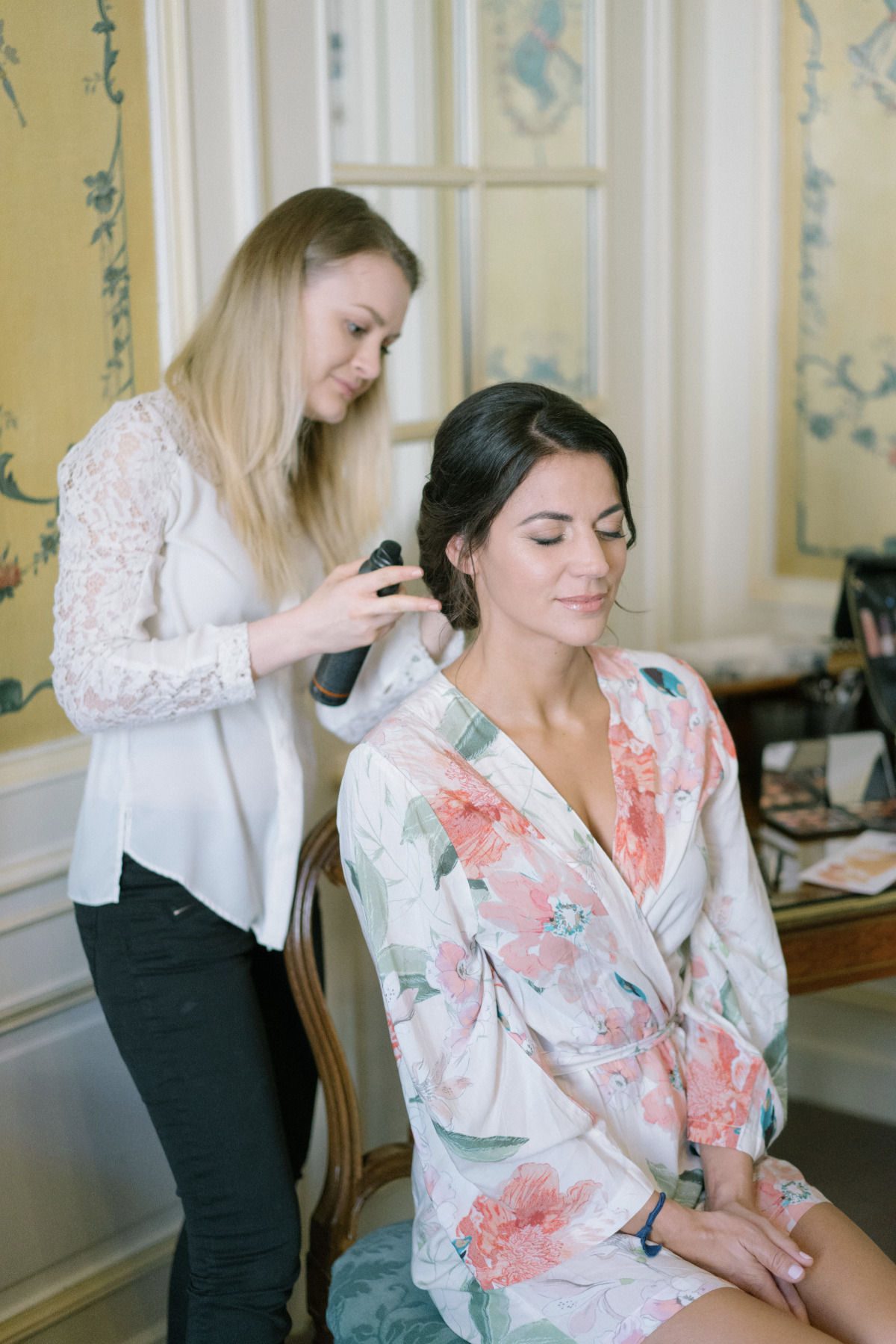 Bride getting hair styled in floral robe for wedding