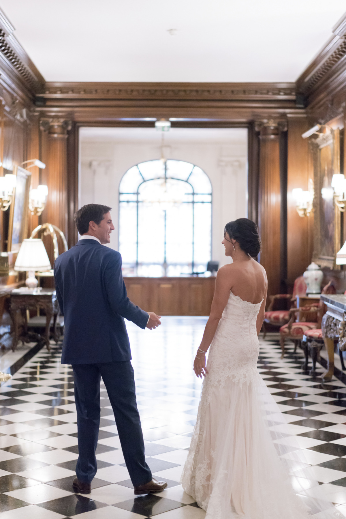 Newlyweds walk away in grand wedding venue hallway