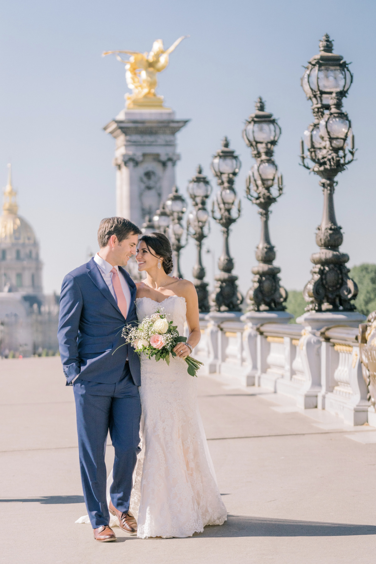Parisian wedding couple on a bridge, holding bouquet