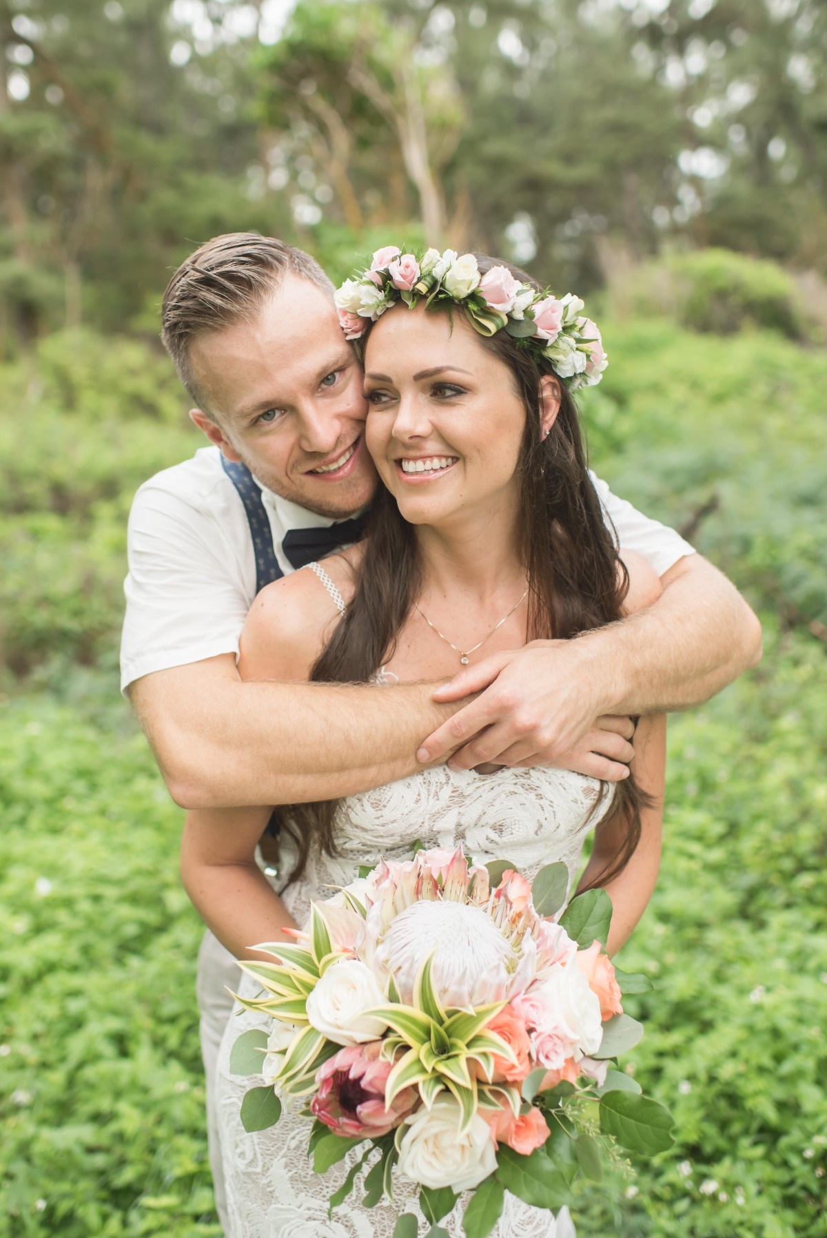 Happy bride with flower crown embraced by groom outdoors