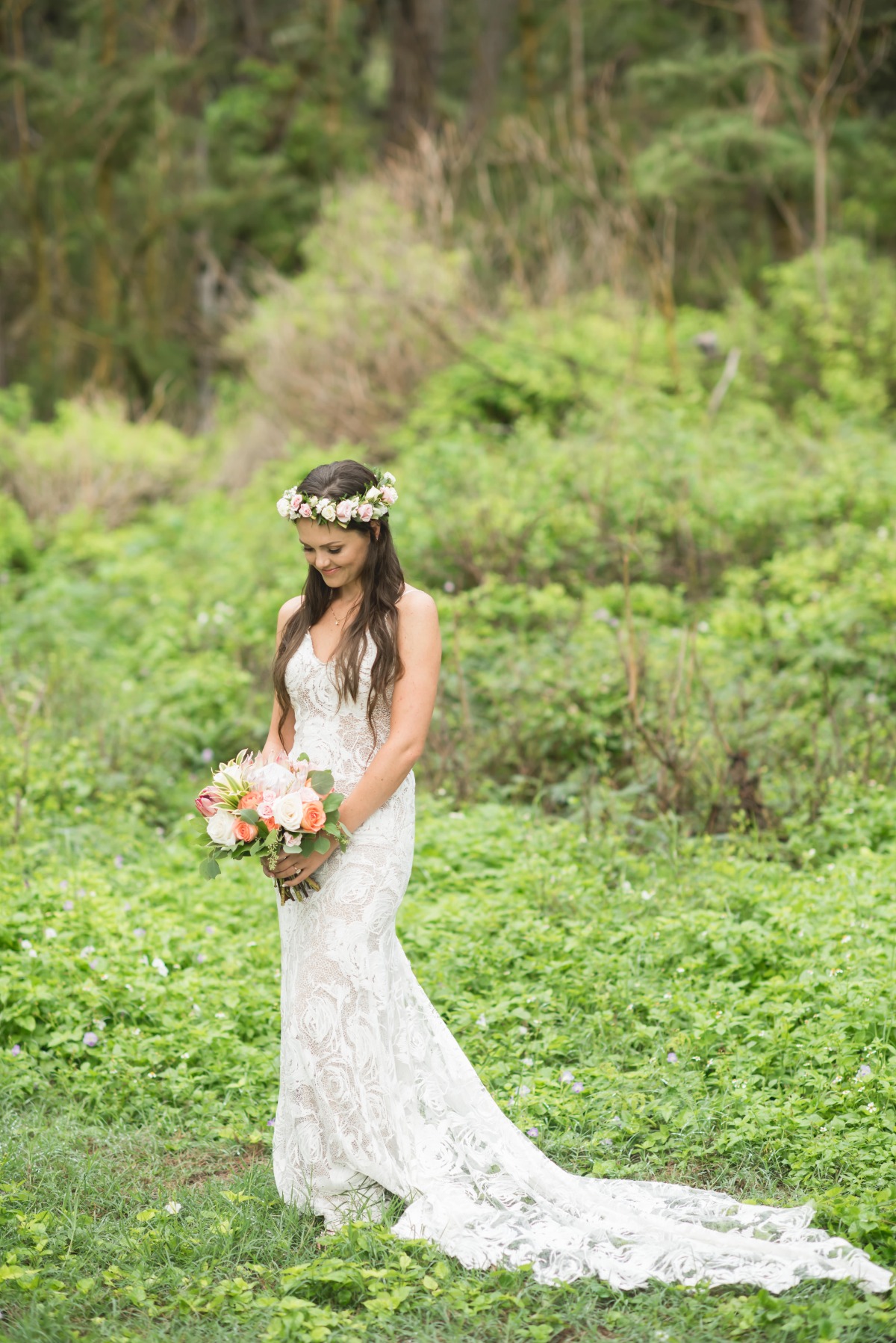 Bride in floral crown and lace dress smiles in a forest setting