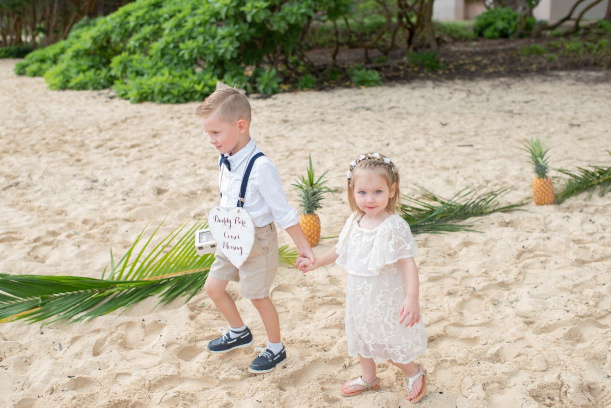 Adorable flower girl and ring bearer at a beach wedding, holding hands