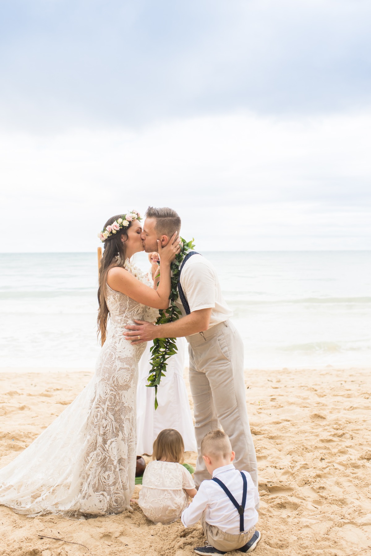 Bride and groom share a kiss on the beach during a wedding ceremony