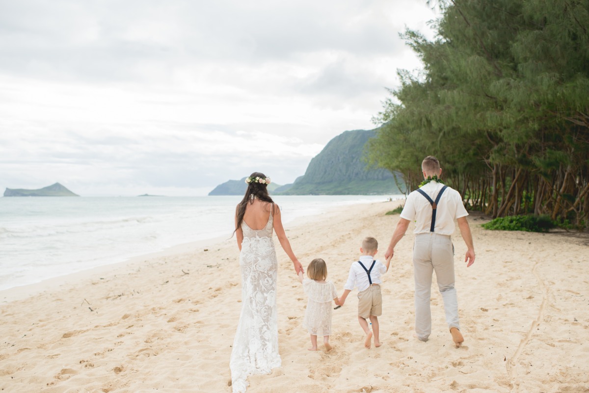 Family walking on a beach, newlywed couple and kids