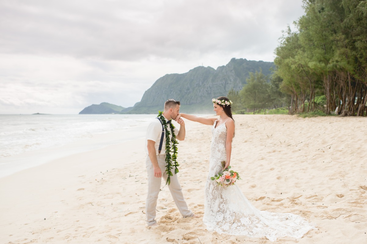 Romantic beach wedding with groom kissing brides hand