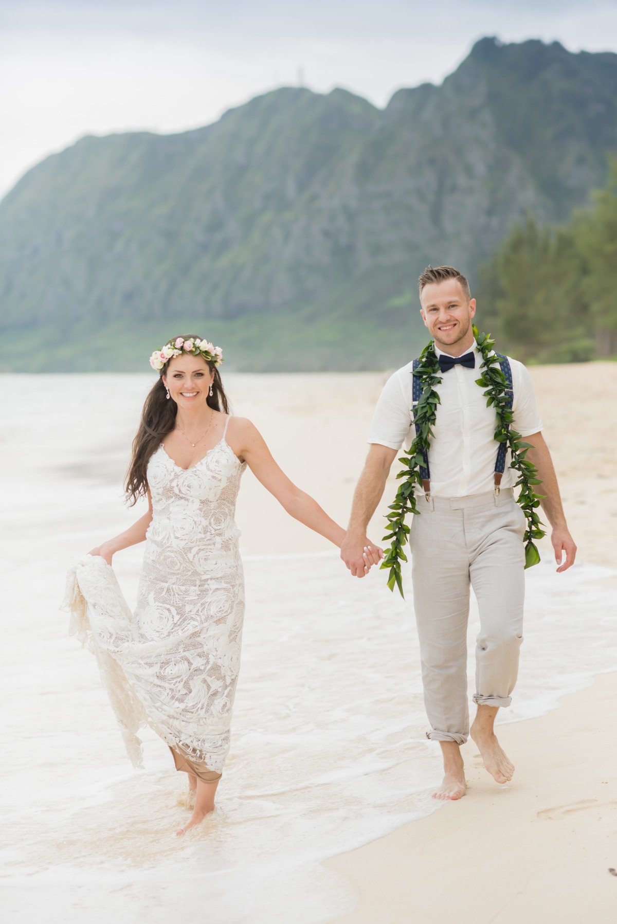 Newlyweds holding hands and walking along the beach after their wedding