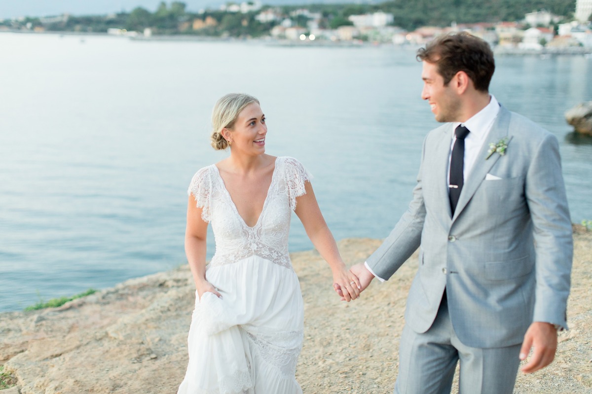 Bride and groom holding hands by the sea at their wedding