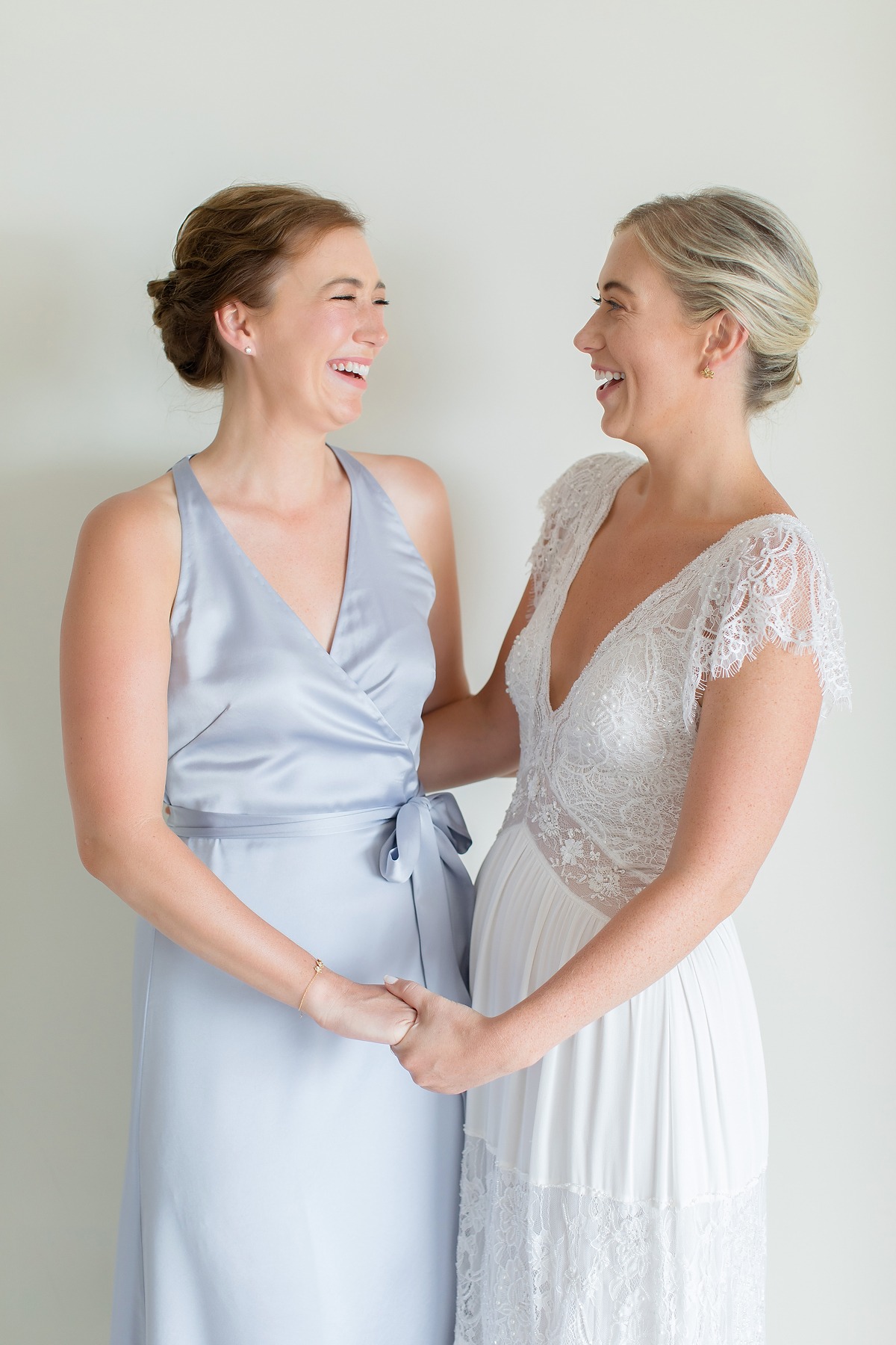 Bride and bridesmaid share a joyful moment laughing