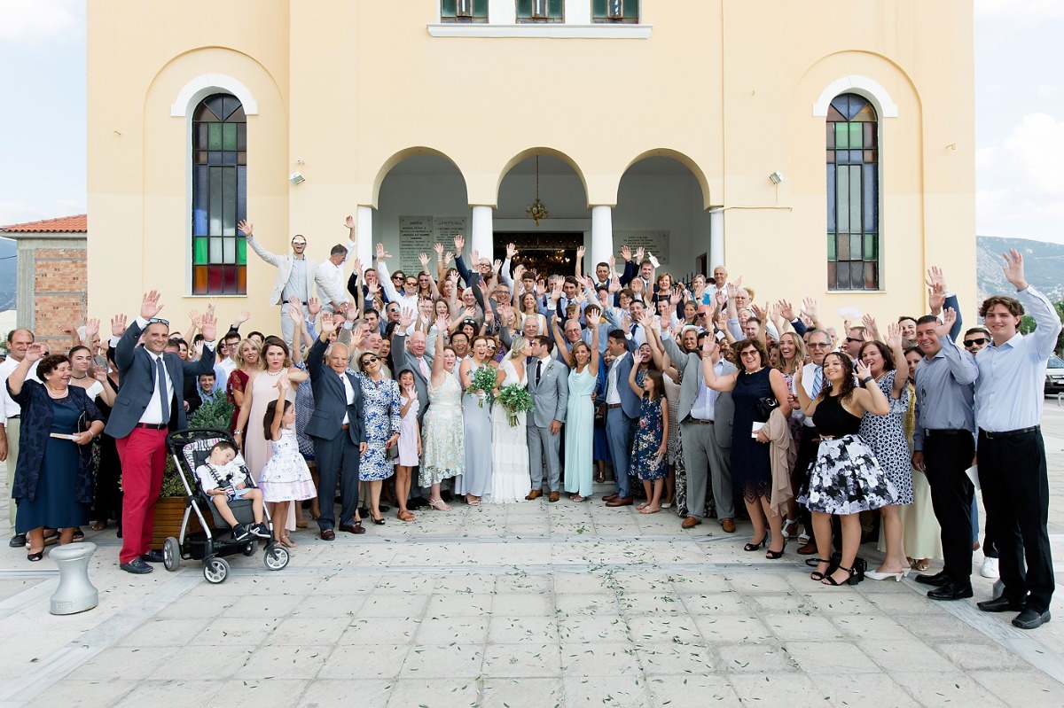 Wedding group photo outside church, happy couple and guests