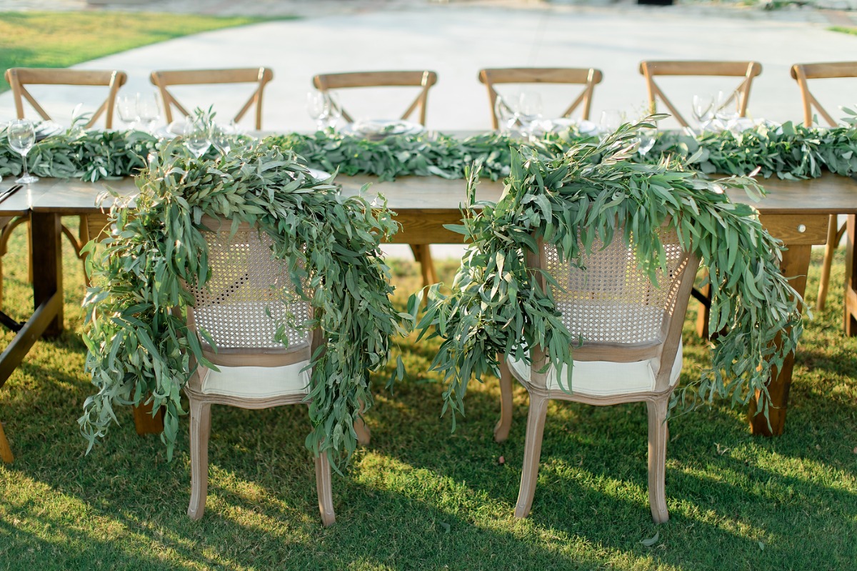 Wedding table with eucalyptus garland and decorated chairs