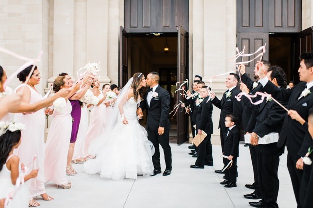 Bride and groom kiss, wedding party celebrates with ribbons