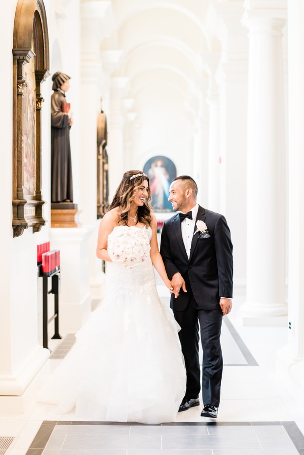 Happy bride and groom walk holding hands in a church