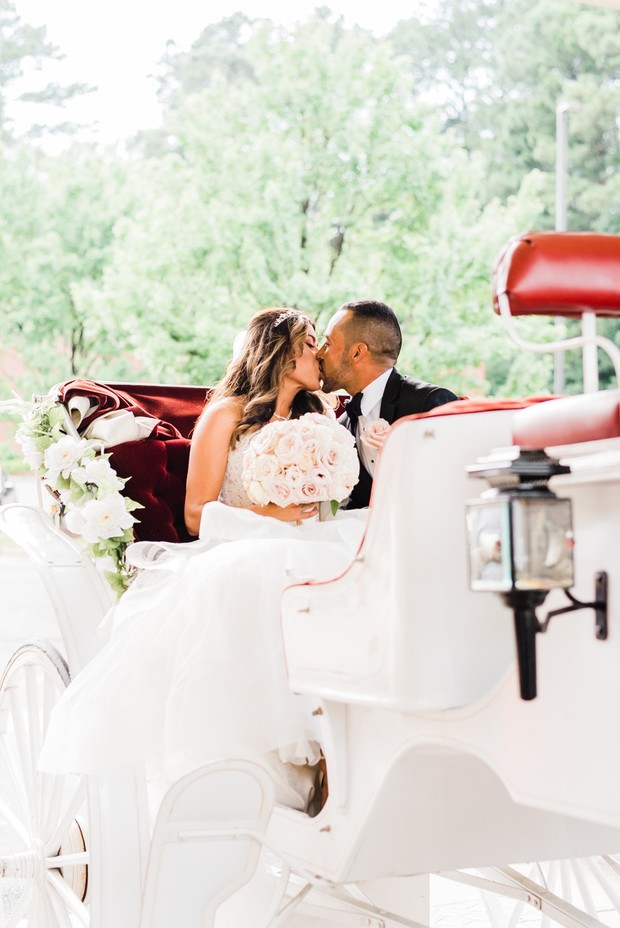 Bride and groom share a kiss in a horse-drawn carriage