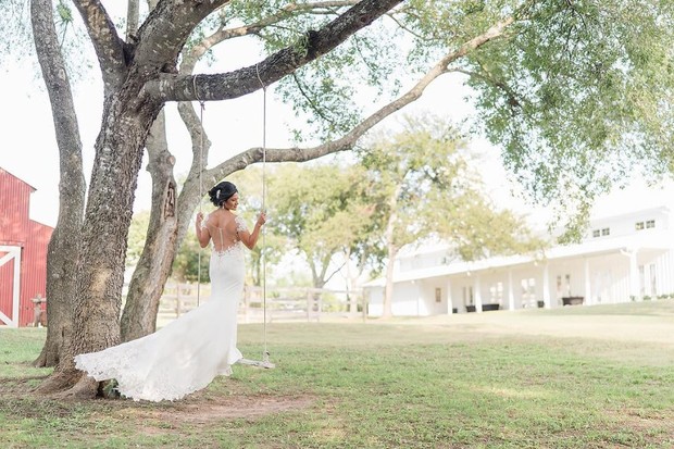 Bride in wedding dress on swing with scenic countryside background