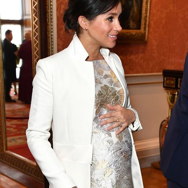Pregnant Meghan Markle in a white coat and floral dress