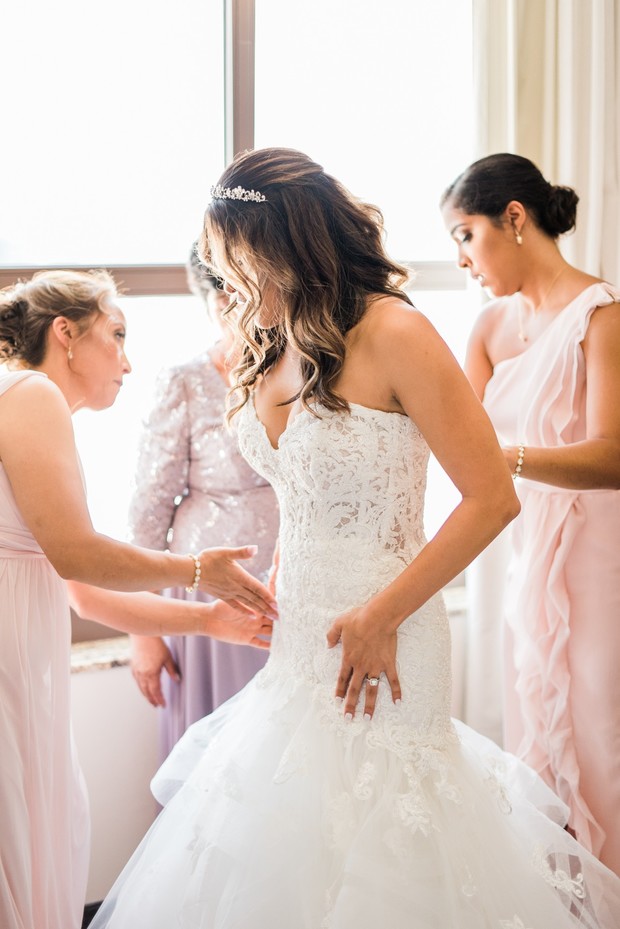 Bride getting dressed in wedding gown with bridesmaids help