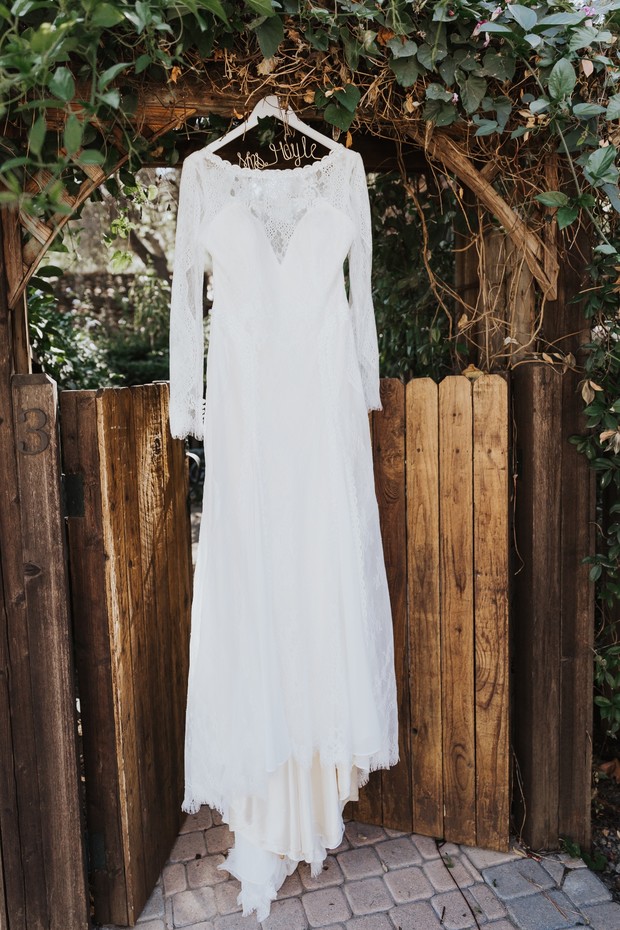Elegant lace wedding gown hanging on rustic wooden gate