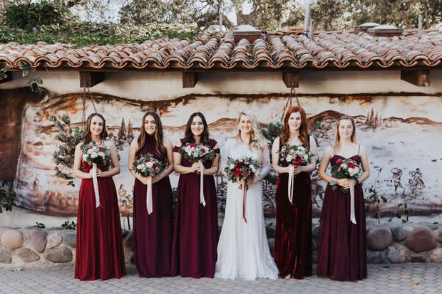 Bride and bridesmaids in burgundy gowns with bouquets
