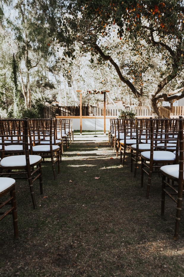 Outdoor wedding ceremony aisle with white chairs under trees