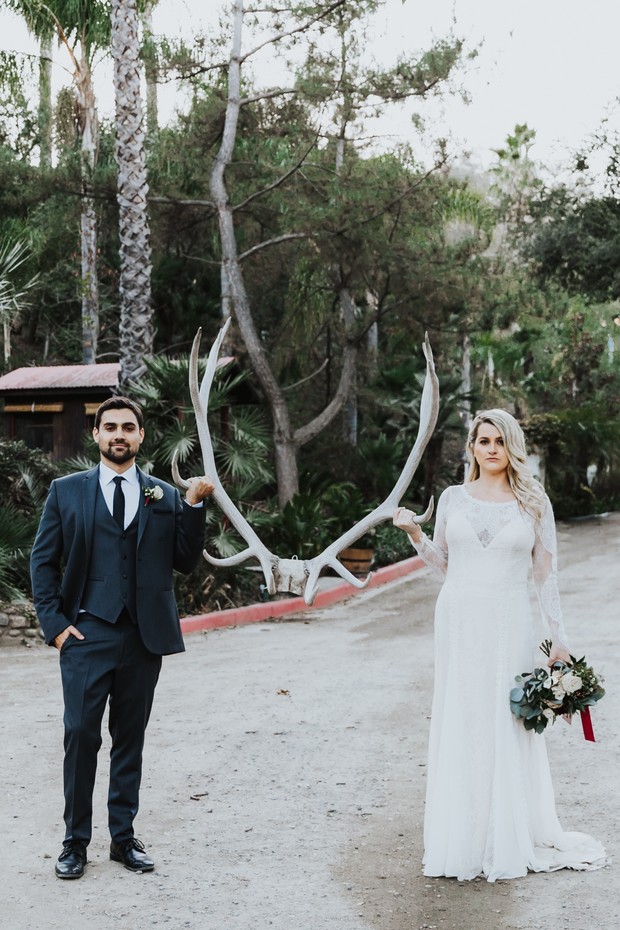 Wedding couple holding antlers smiling on their special day