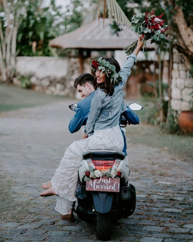Newlyweds ride off on scooter, just married sign