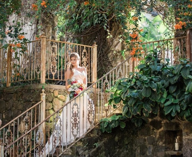 Bride descends ornate garden stairs in wedding gown