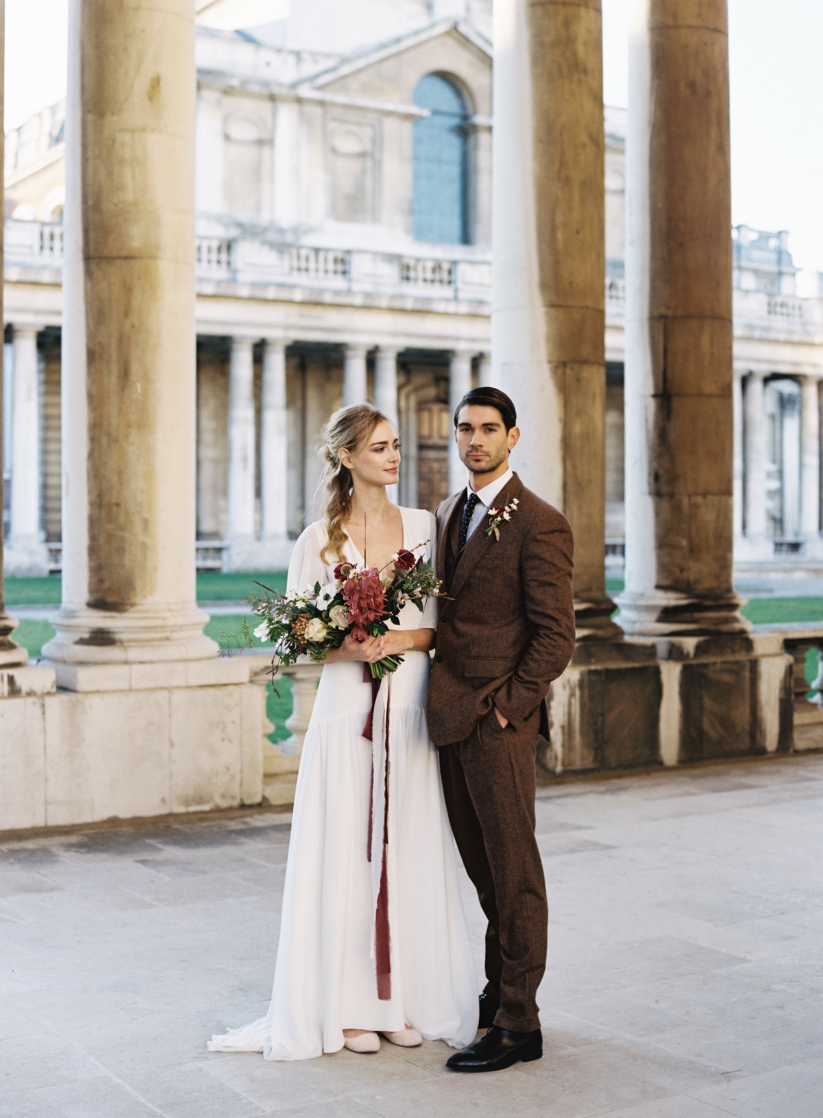 Elegant bride and groom pose in front of grand architecture