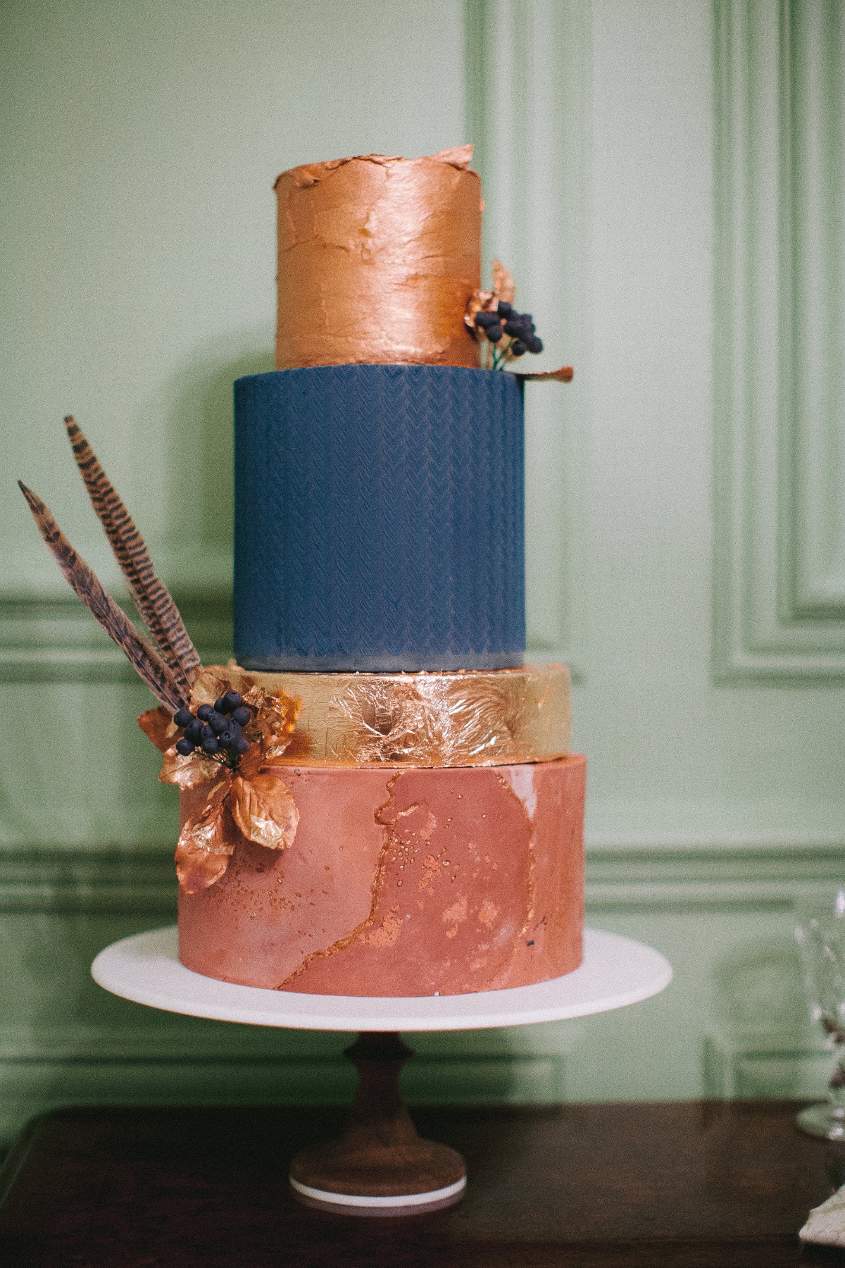 Elegant three-tiered wedding cake in copper, blue, and gold