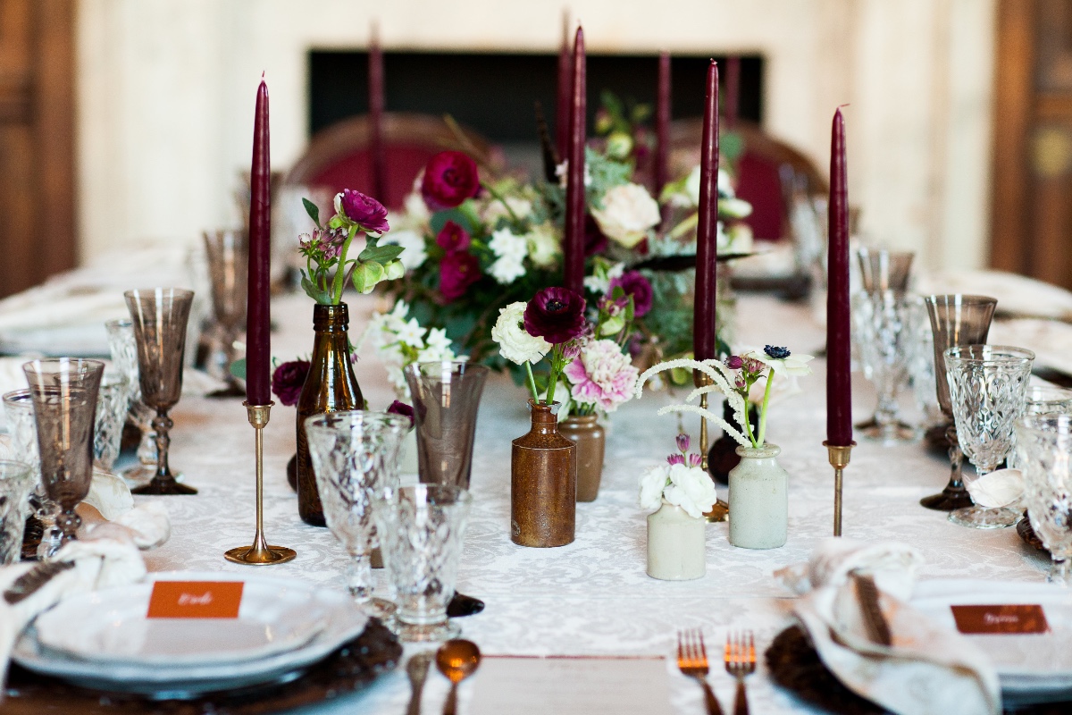 Elegant wedding table setting with burgundy candles and floral arrangements