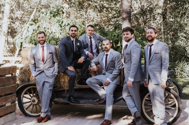 Groomsmen pose on a vintage car for a rustic wedding photo