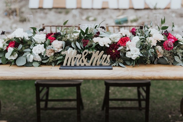 Wedding table setting with floral arrangement and Mrs & Mrs sign