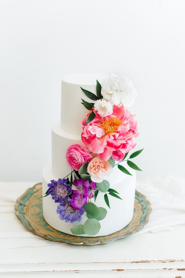 Elegant white wedding cake adorned with colorful fresh flowers