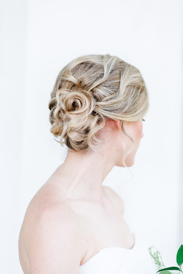 Blonde bridal updo with a rose shaped hair arrangement