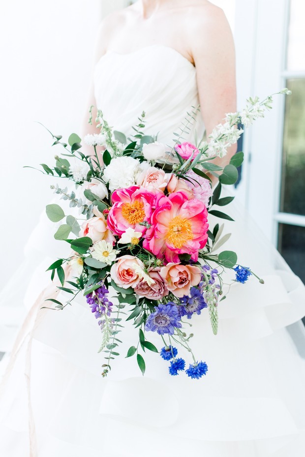 Bride holding a bright pink and blue floral wedding bouquet