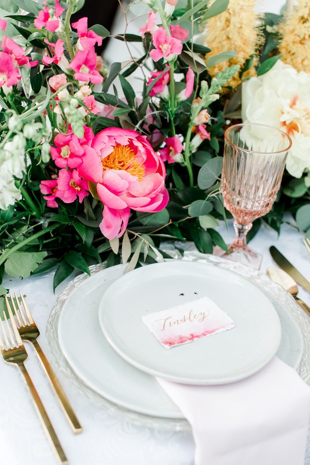 Elegant wedding place setting with pink floral centerpiece