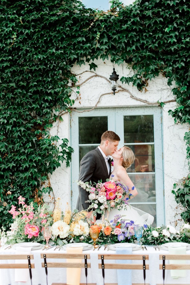 Romantic wedding kiss near floral adorned reception table