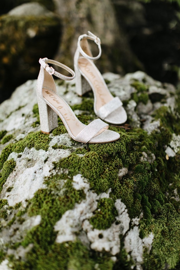 Elegant bridal heels sparkle on a mossy stone surface