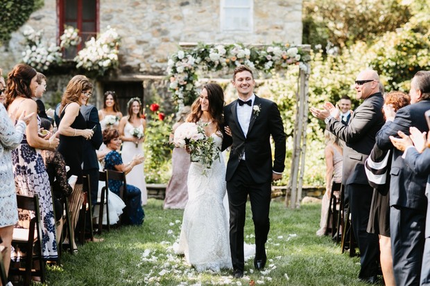 Newlyweds walk aisle at outdoor garden wedding ceremony