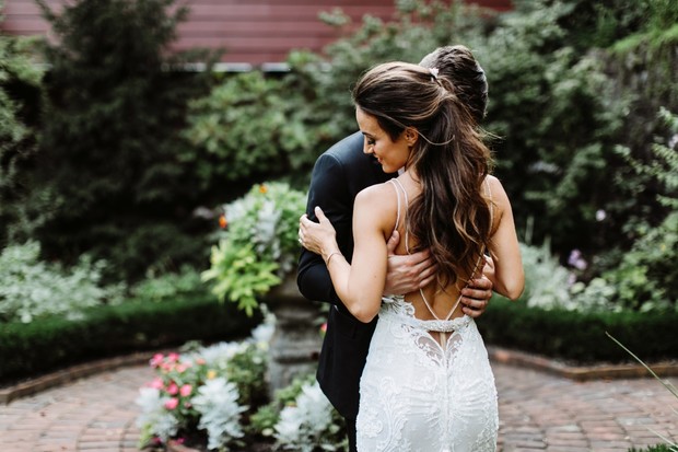 Bride and groom embrace at garden wedding ceremony