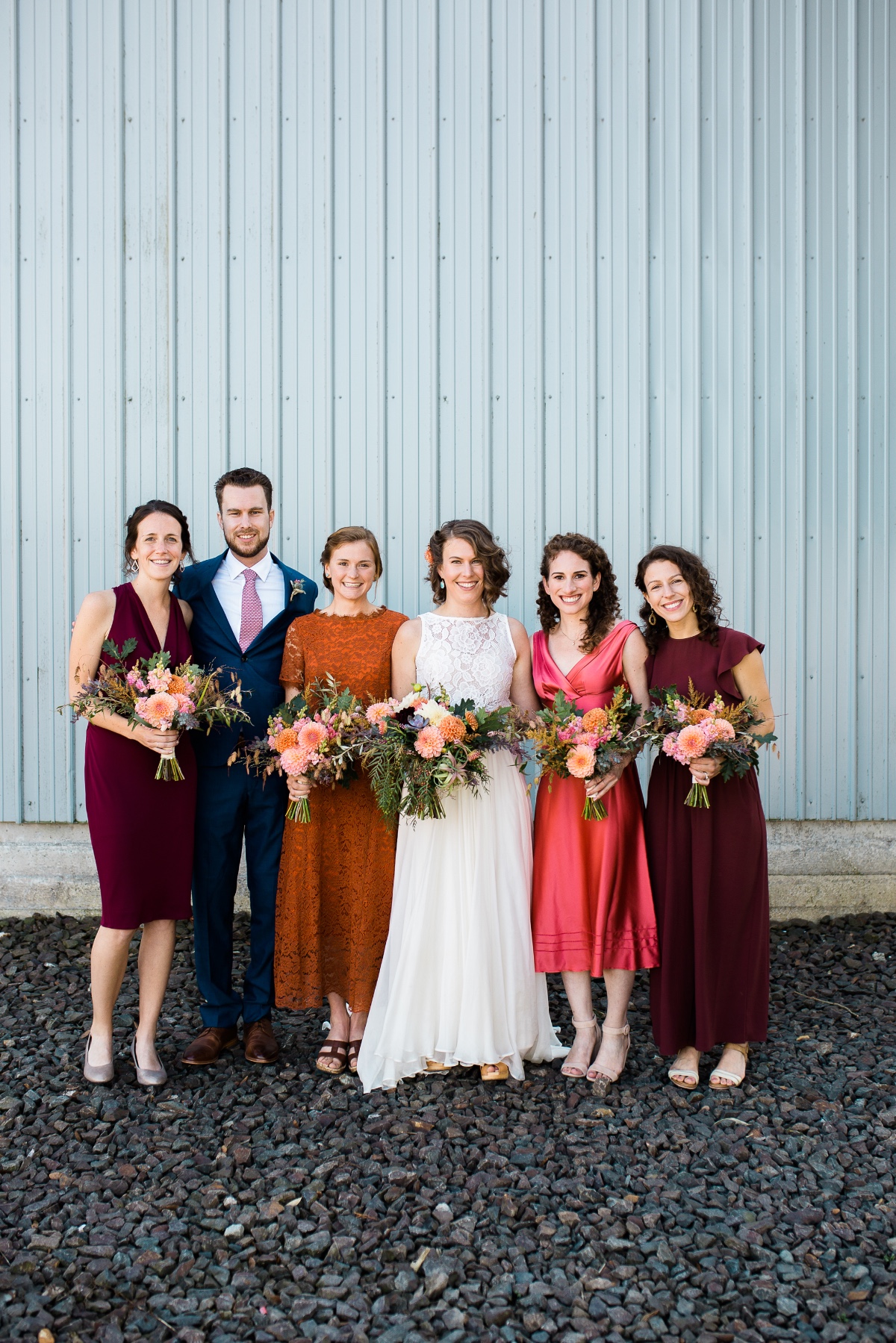 Bridal party poses with flowers at outdoor wedding venue